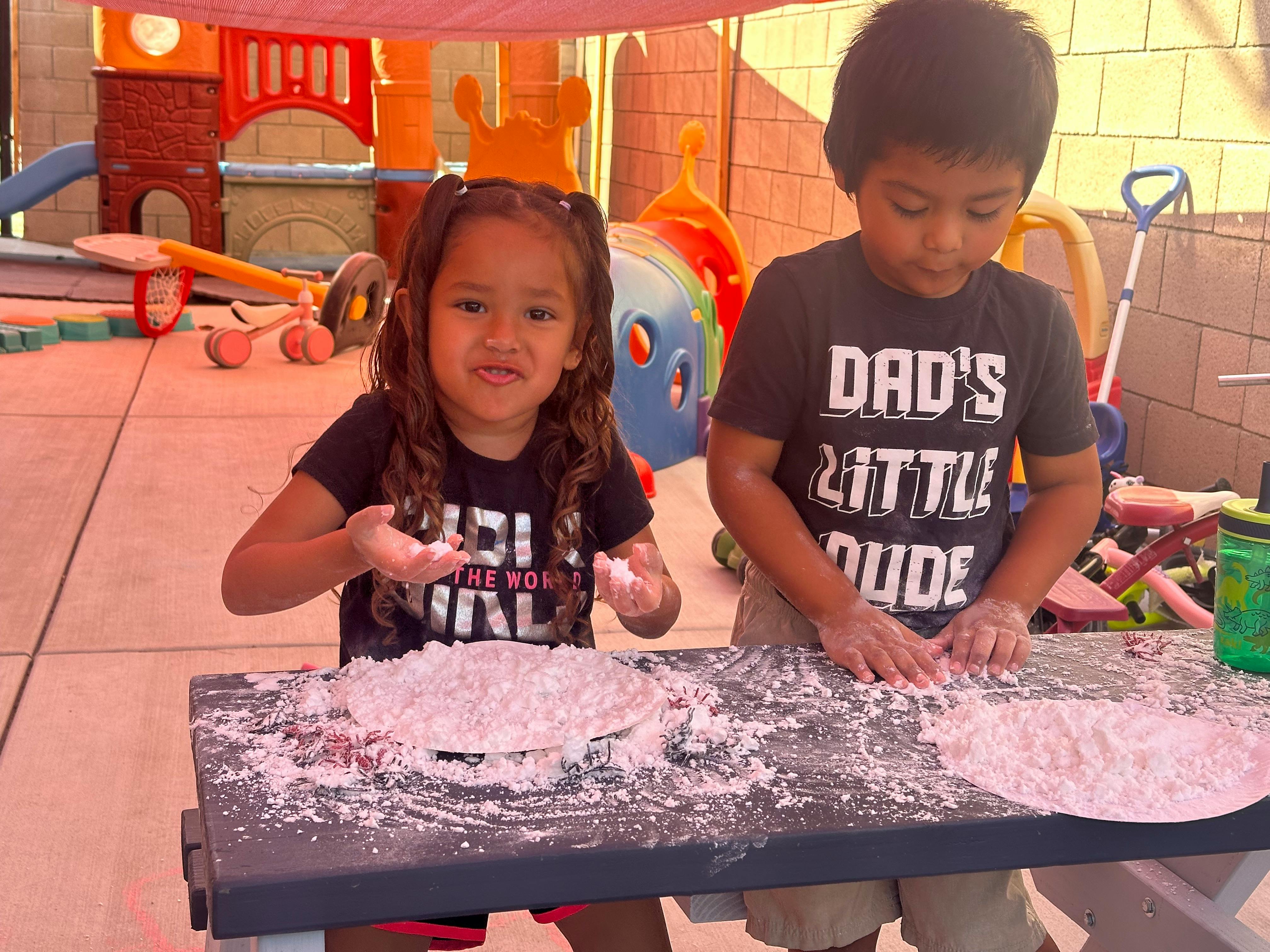 Two children playing with flour on a table