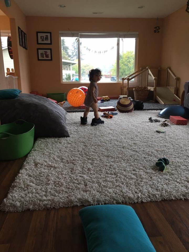 Child standing on a rug in a room with toys