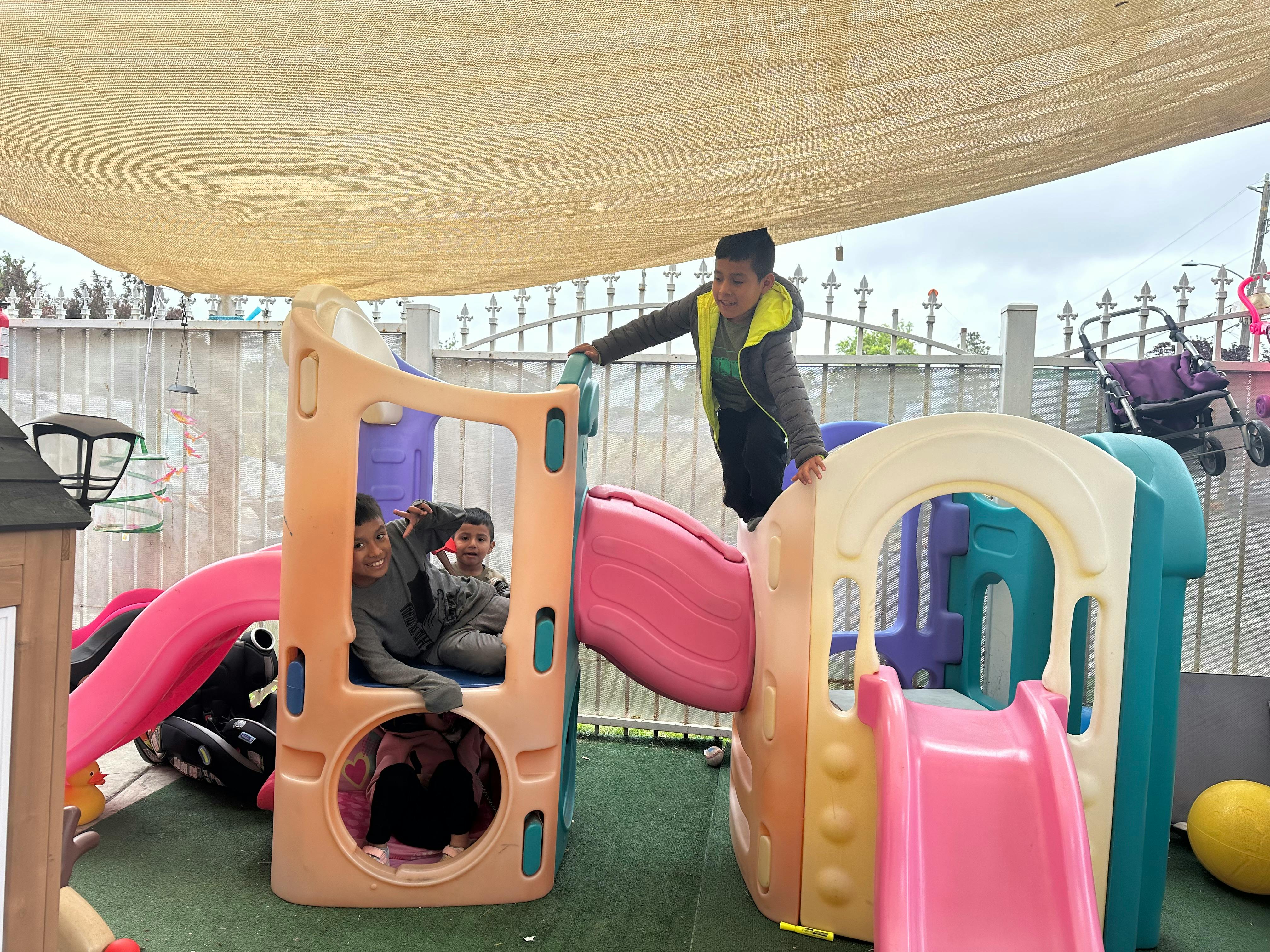 Children playing on a colorful outdoor play structure with slides