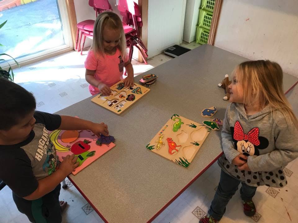 Three children playing with puzzles at a table