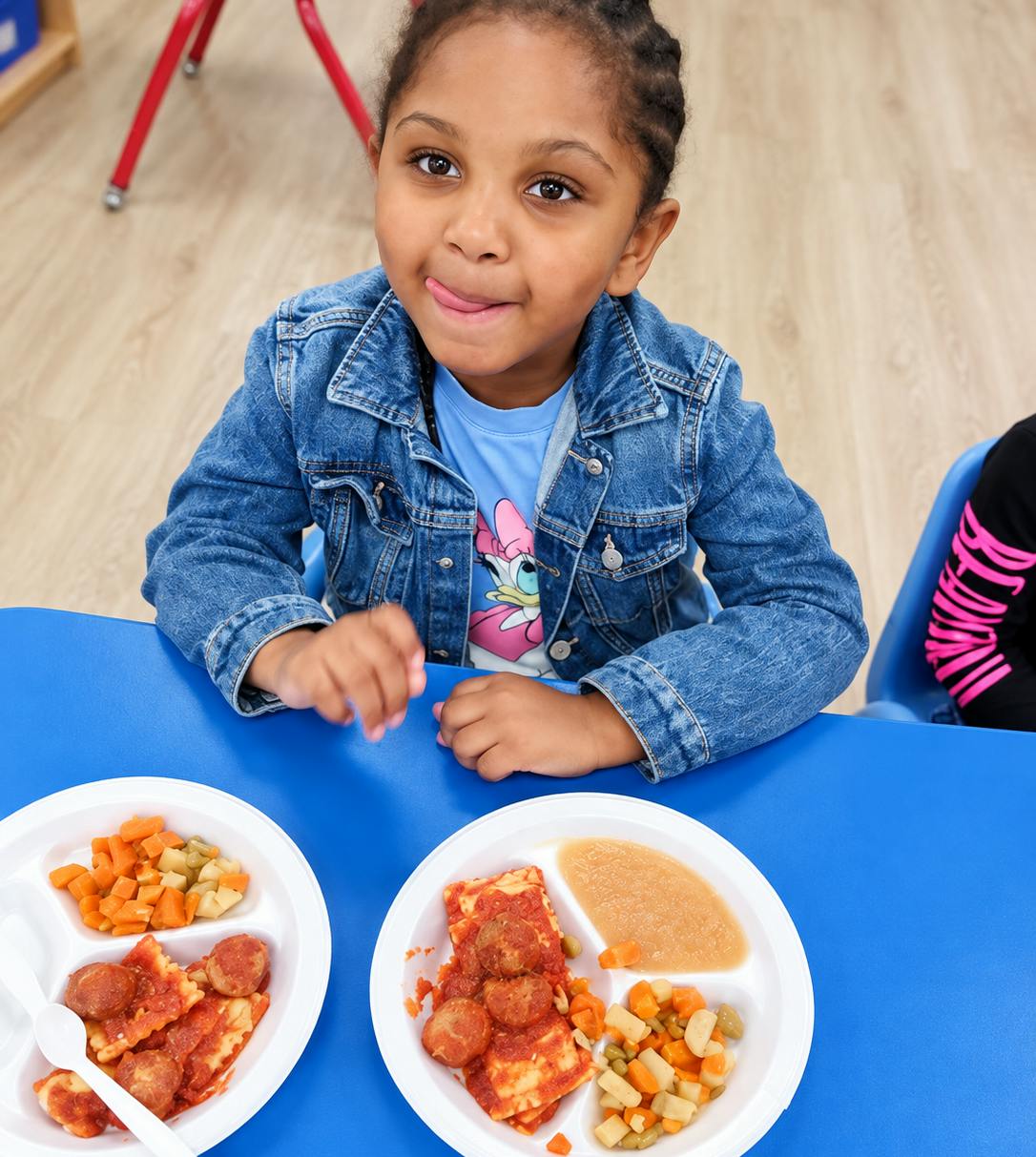 Child sitting at a table with plates of food