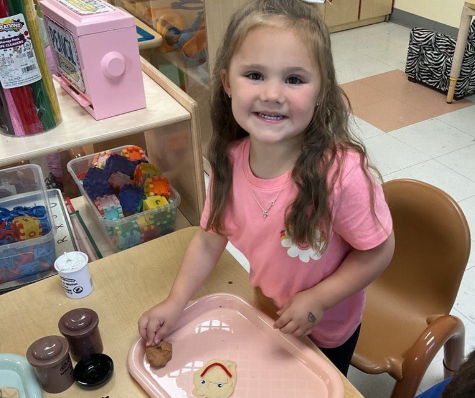 Child at a table with a pink tray and small containers