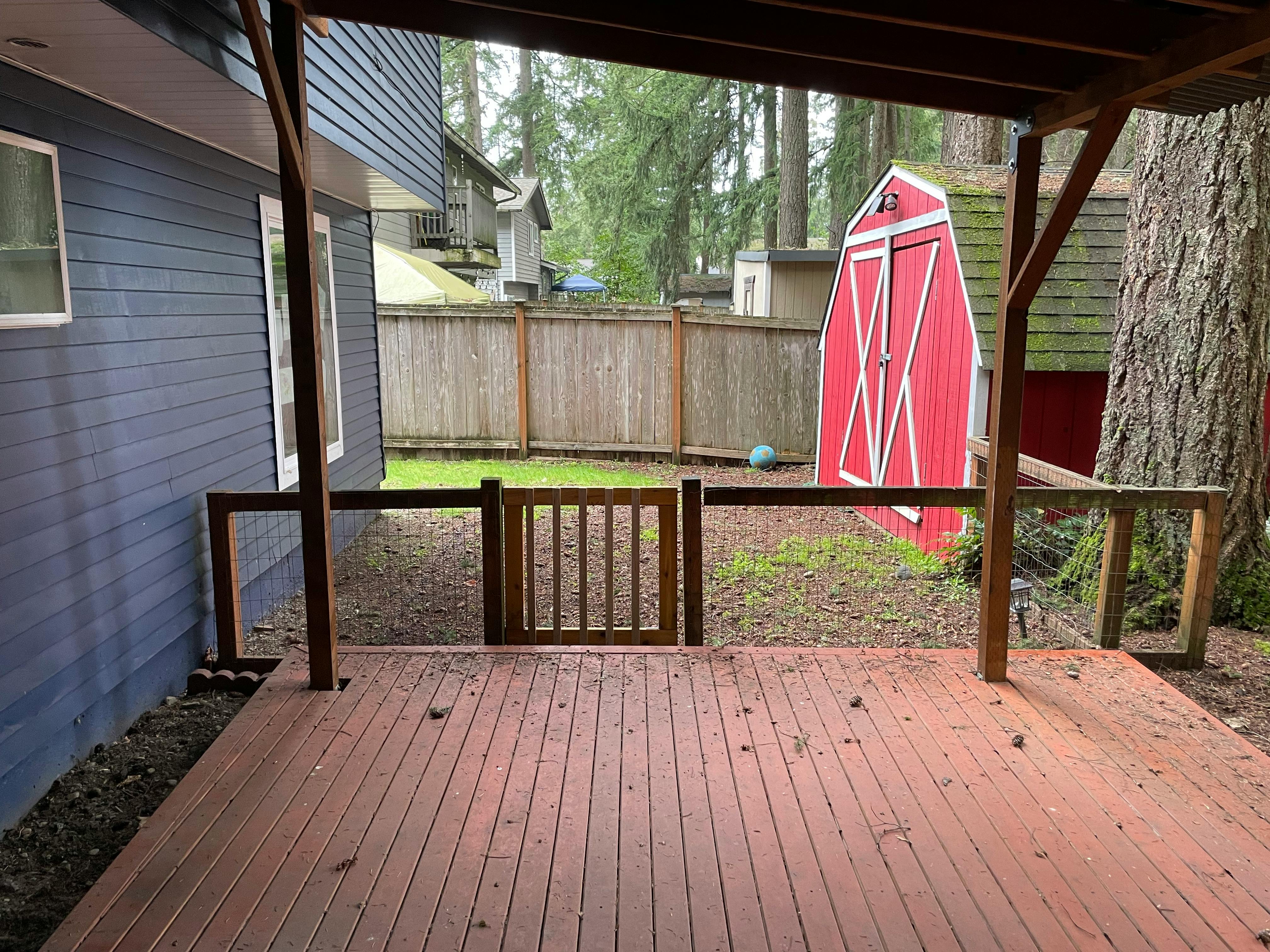 Wooden deck with a small gate leading to a fenced yard and grassy backyard