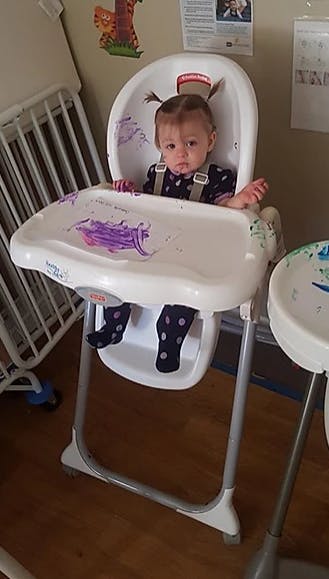 Child in a high chair with purple food on the tray and face