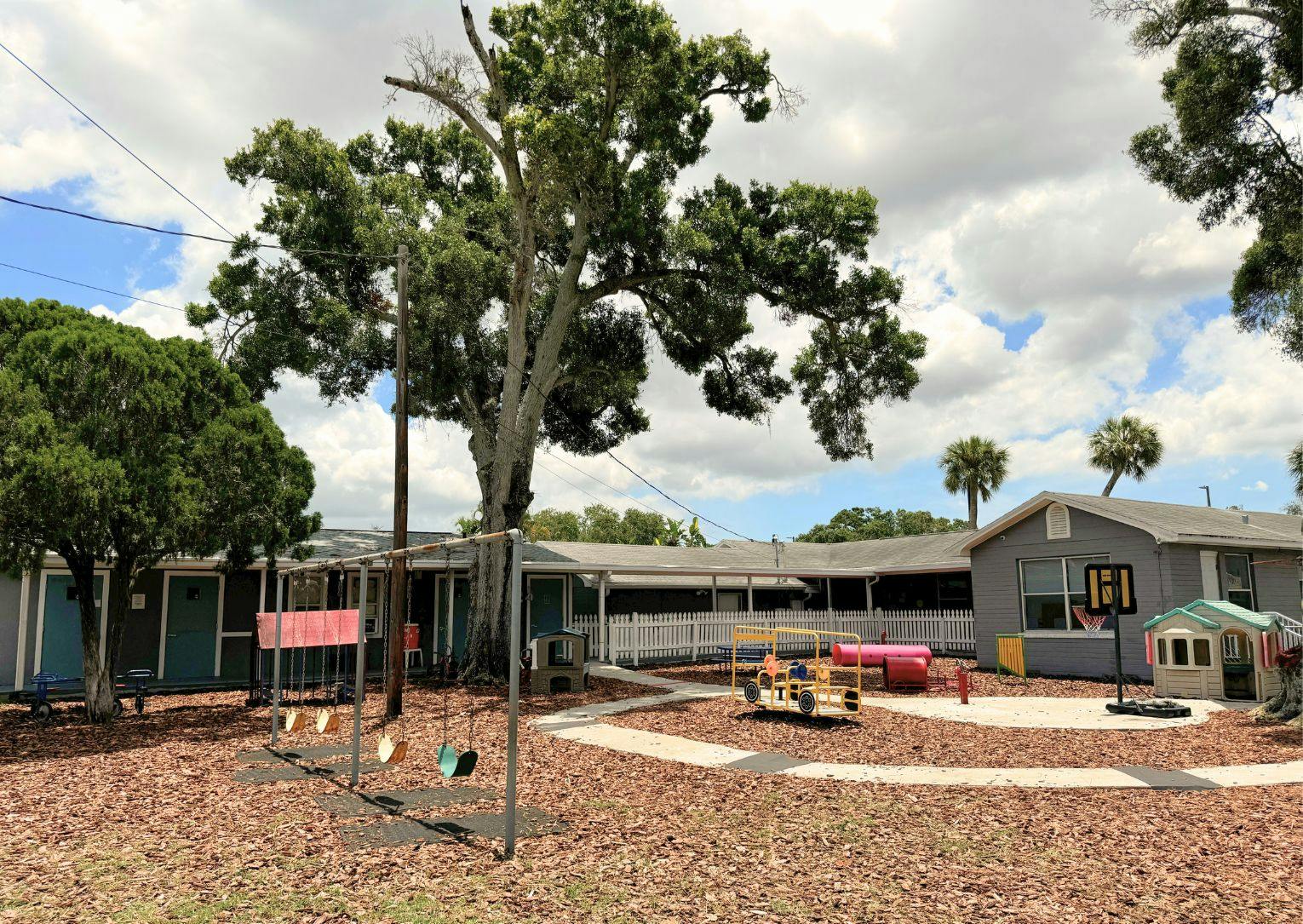 Outdoor playground with swings and play structures in front of a building