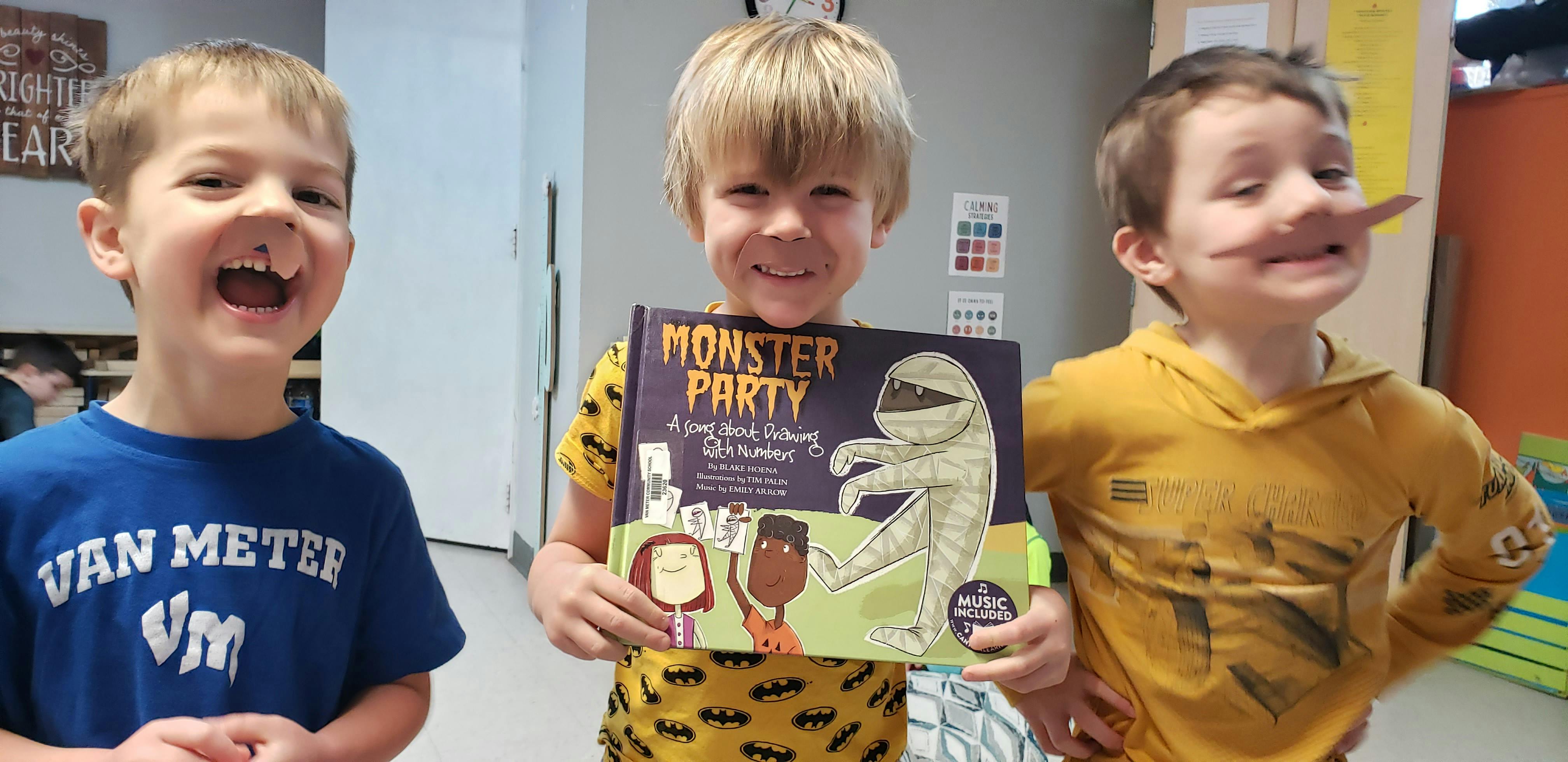 Three children, one holding a book titled "Monster Party"