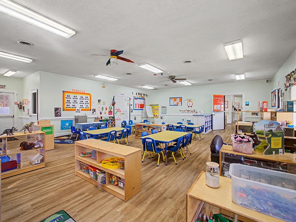 Classroom with child-sized tables and chairs, educational posters on walls