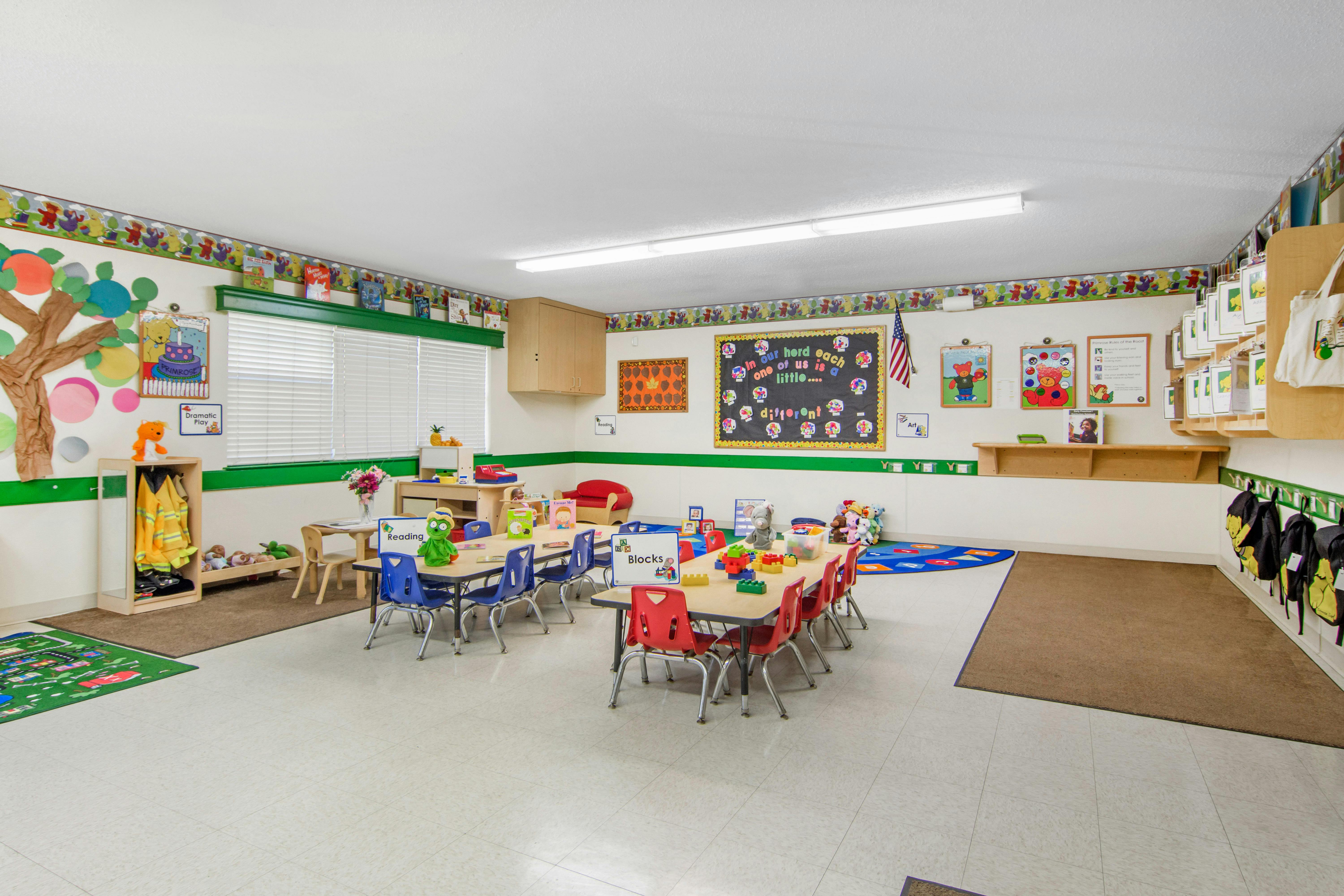 Classroom with small tables and chairs, play areas, and educational decorations