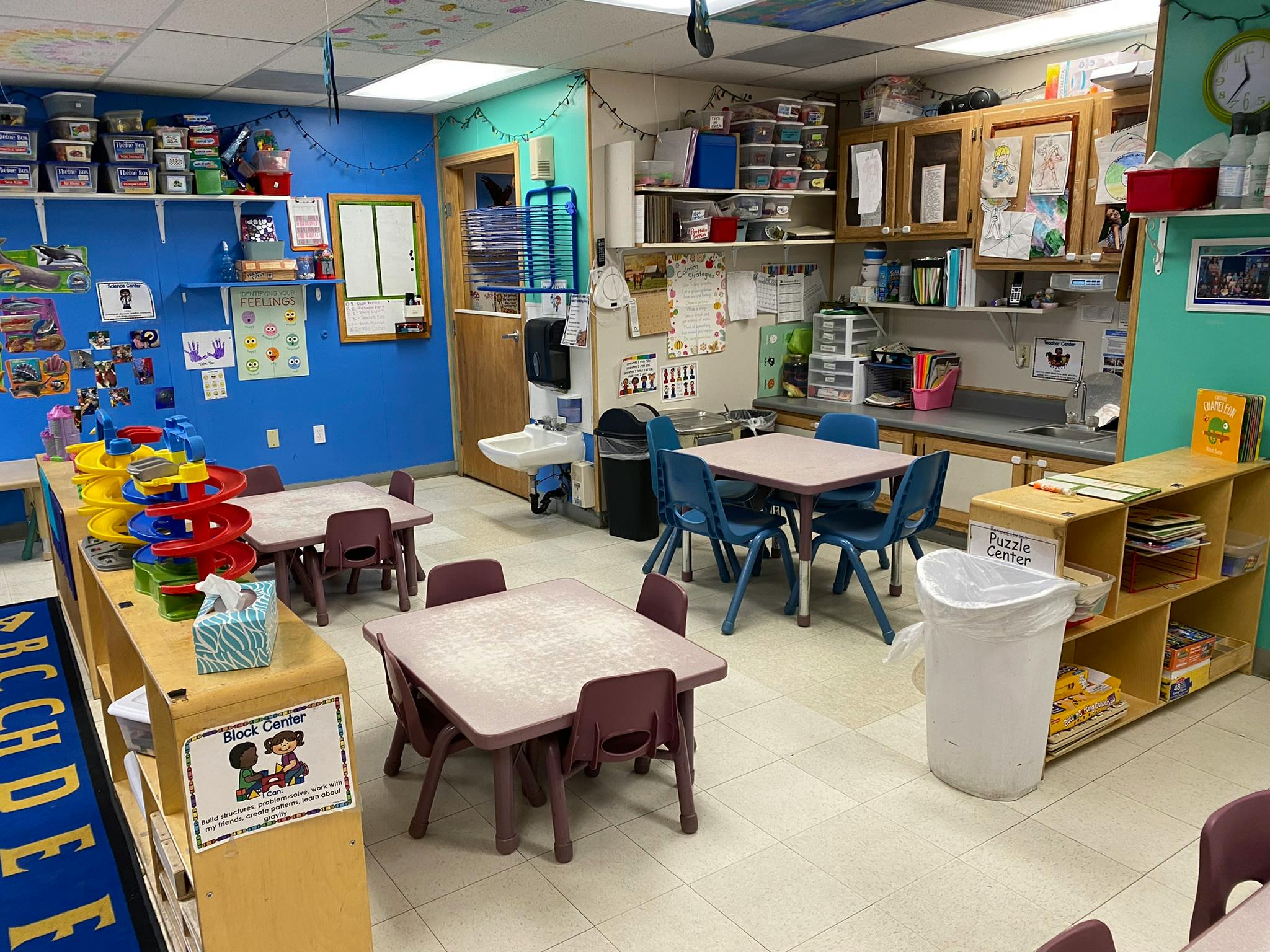 An empty early childhood classroom with small tables and chairs