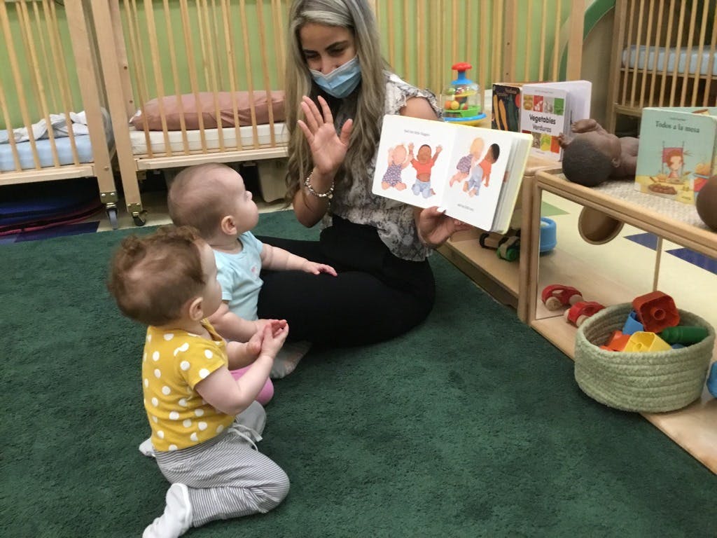 Person in mask reading a book to two children