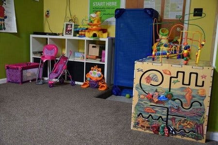 Children's play area with toys, a cot, and storage shelves