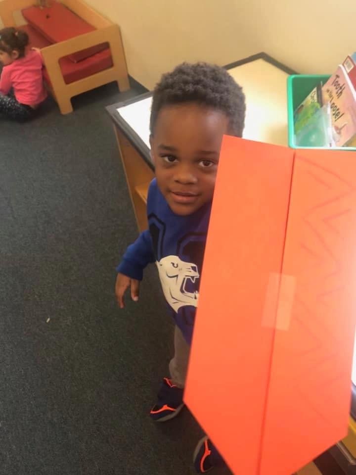 Child peeking from behind an orange divider