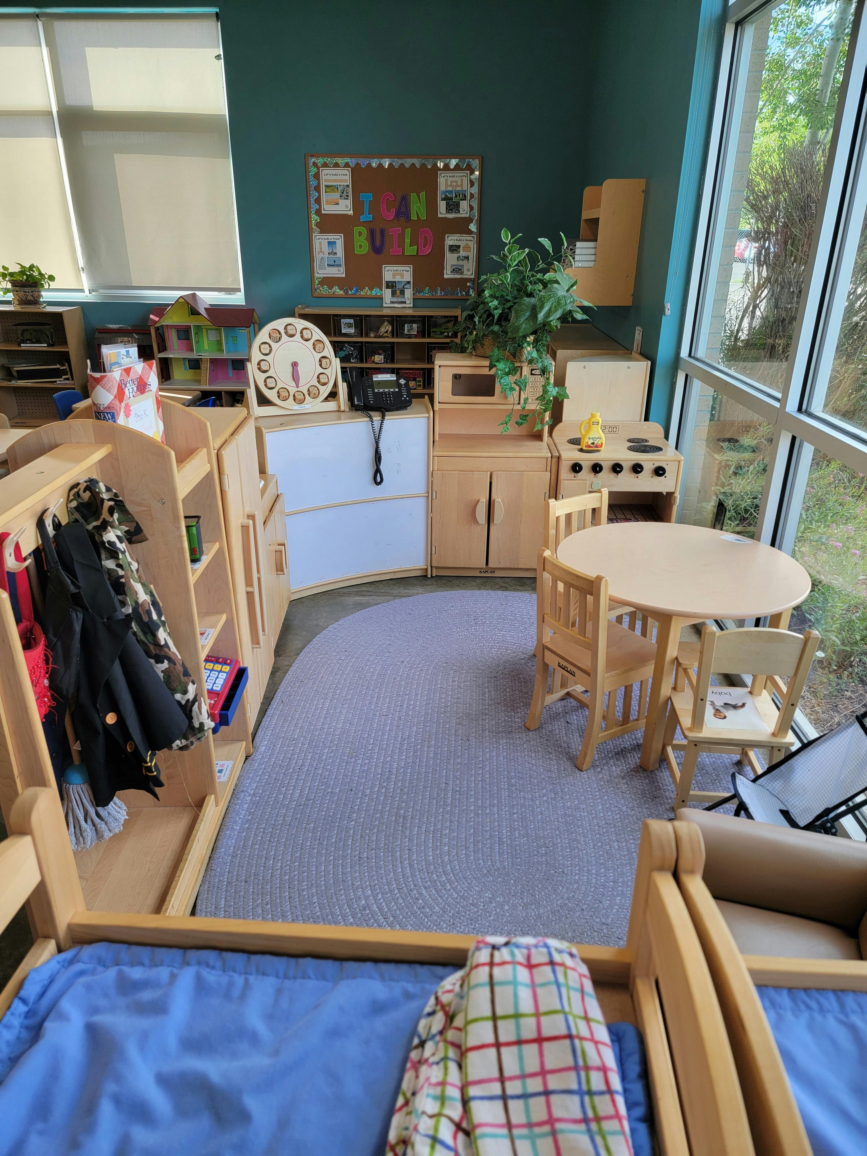 Classroom with small tables and chairs, play kitchen, and cubbies