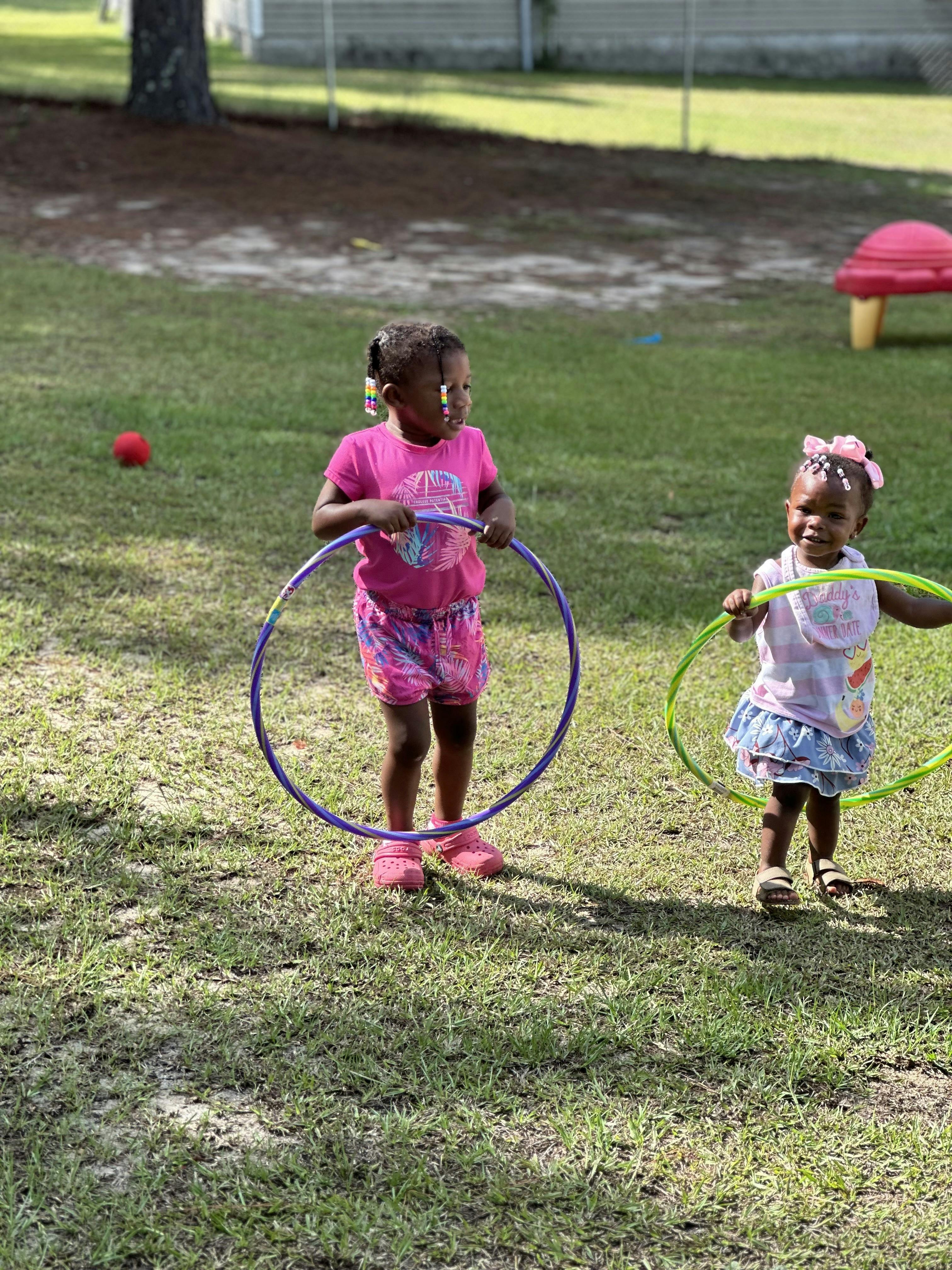 Two children holding hula hoops outdoors