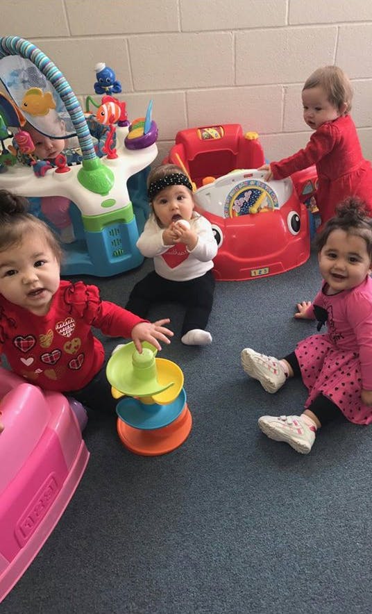 Three children playing with toys on a carpeted floor