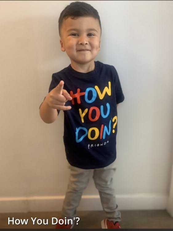 Child in a "How You Doin'?" shirt pointing forward