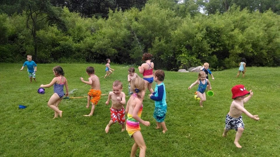 Children in swimsuits running on grass