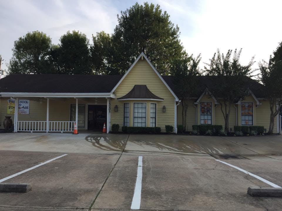 Yellow building with a porch and a parking lot in front