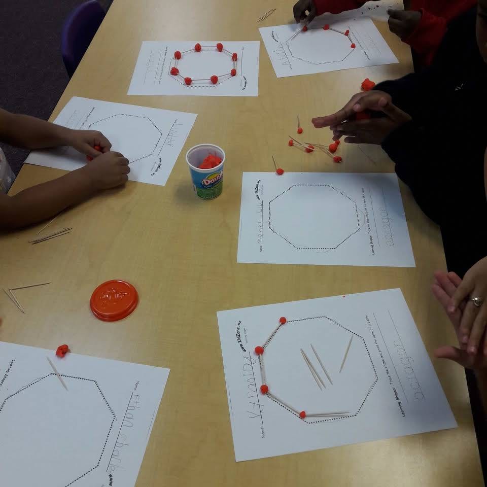 People working on geometry activities with pins and string on paper