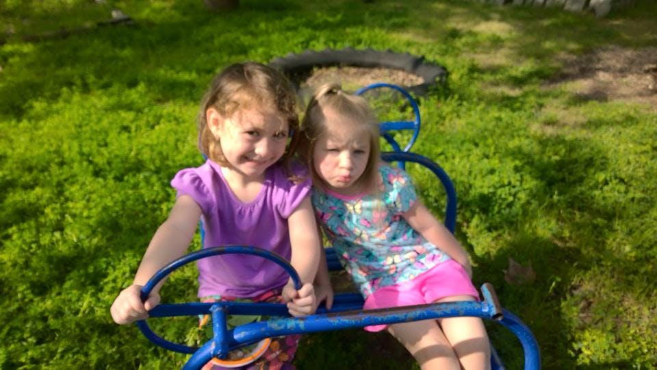 Two children sitting on a blue playground ride