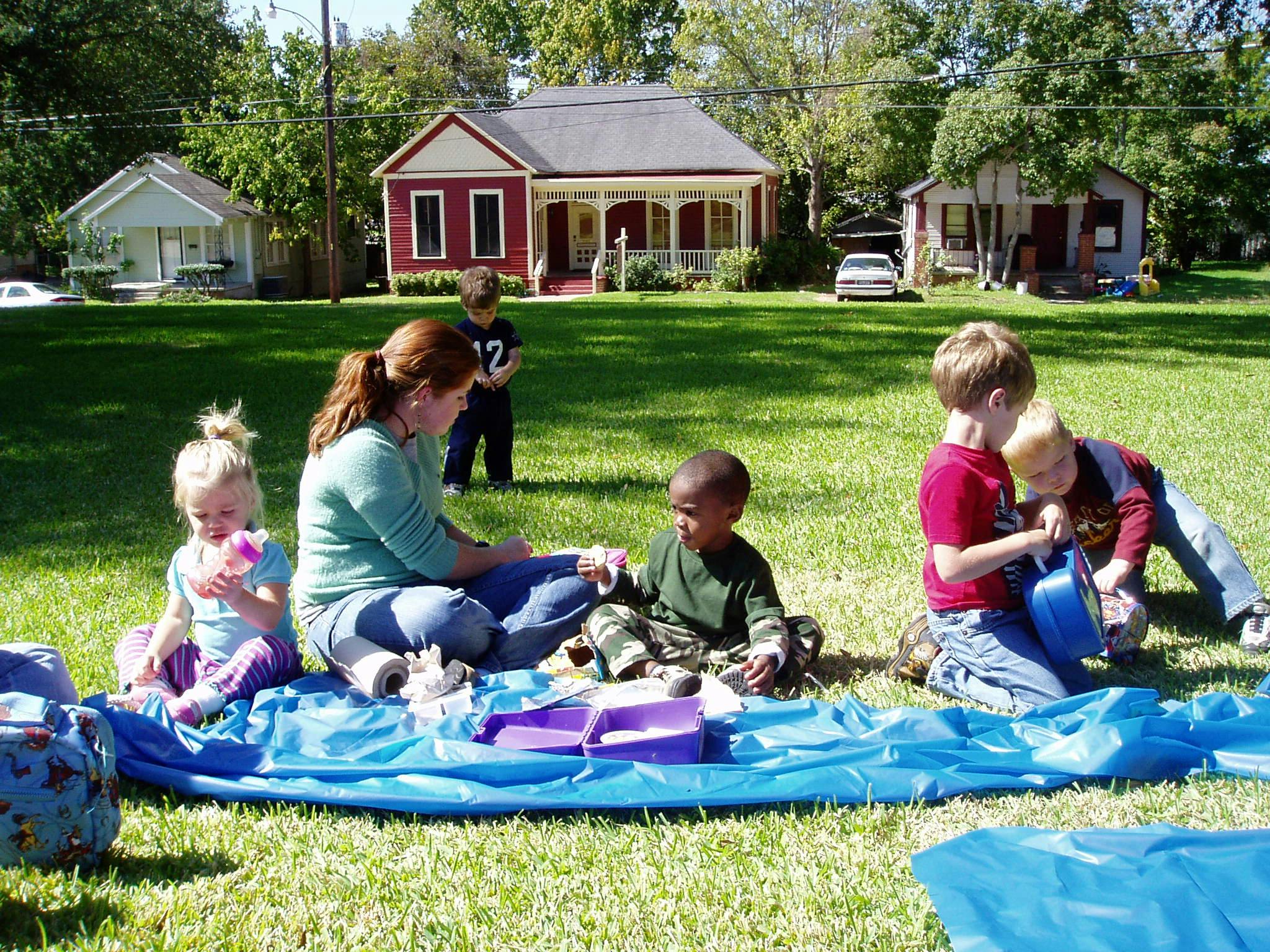 Adult and children sitting on a blue tarp on grass