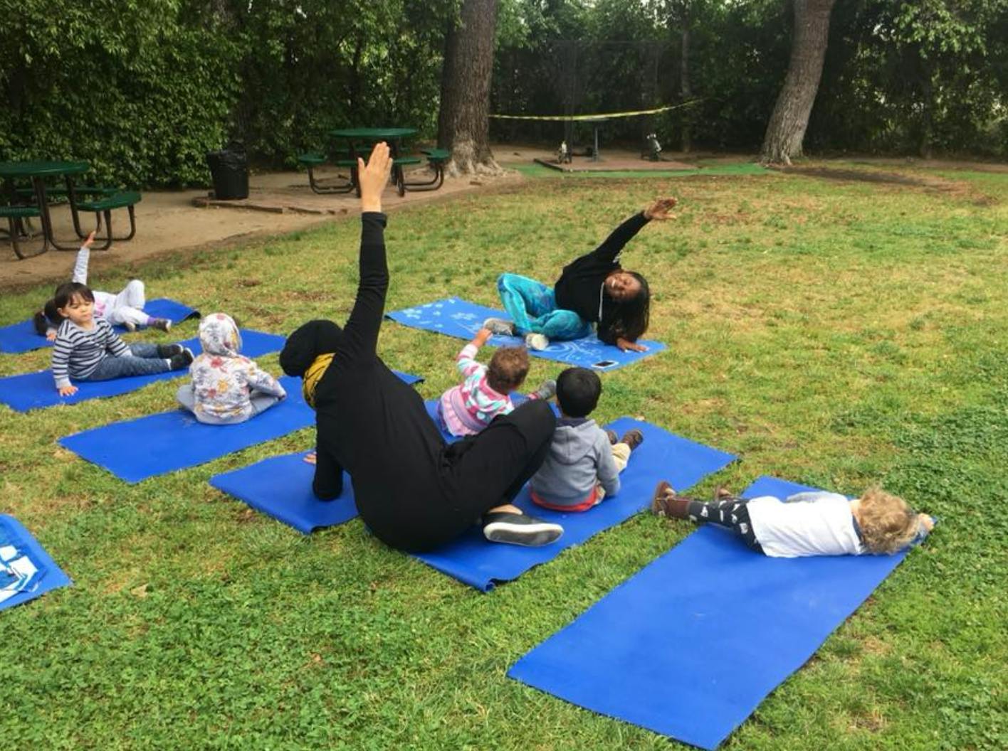 People and children on yoga mats outdoors