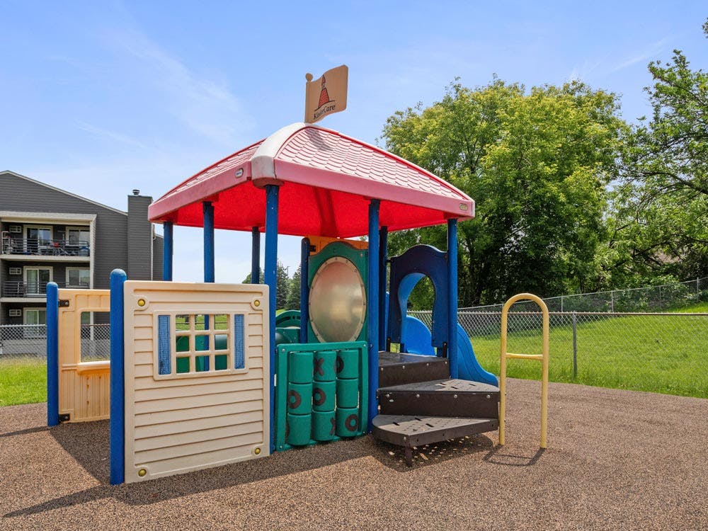 Colorful playground structure with a red roof and steps on a sunny day