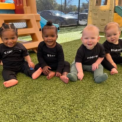 Four babies sitting on artificial grass