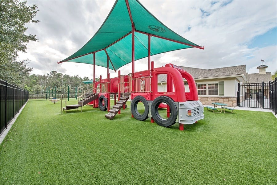 Playground with a red fire truck structure and green shade canopy