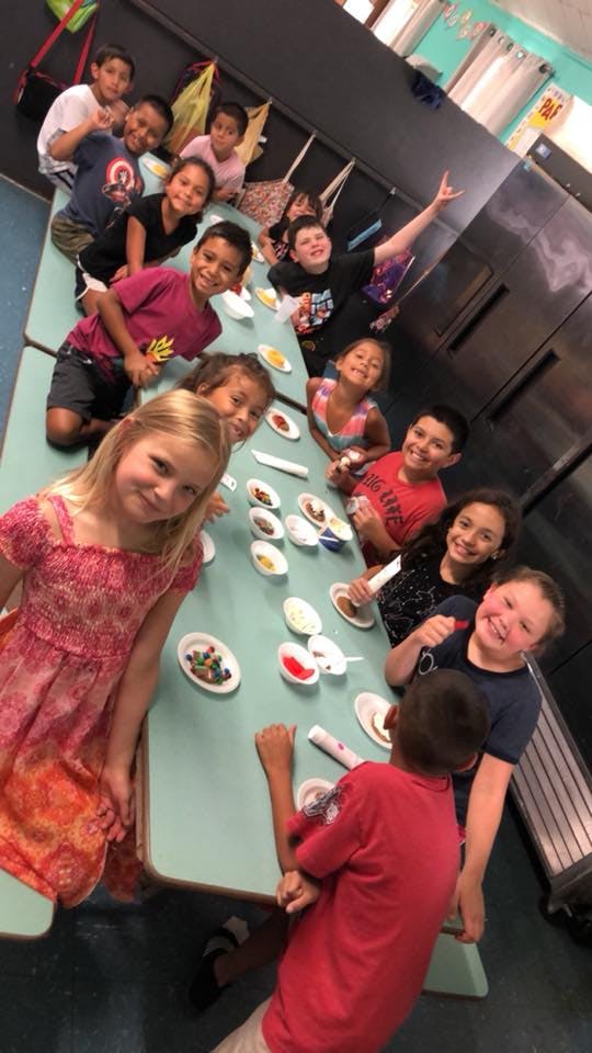 Group of children sitting at a table with small dishes of food