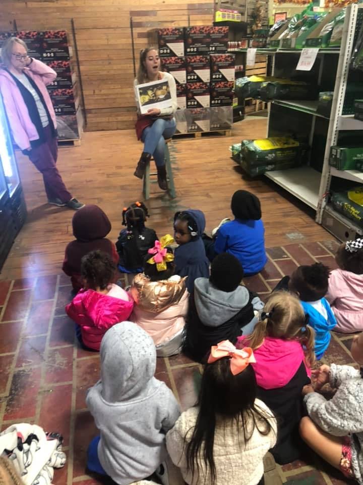 Person reading a book to a group of children sitting on the floor
