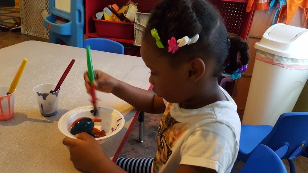 Child painting an object in a bowl