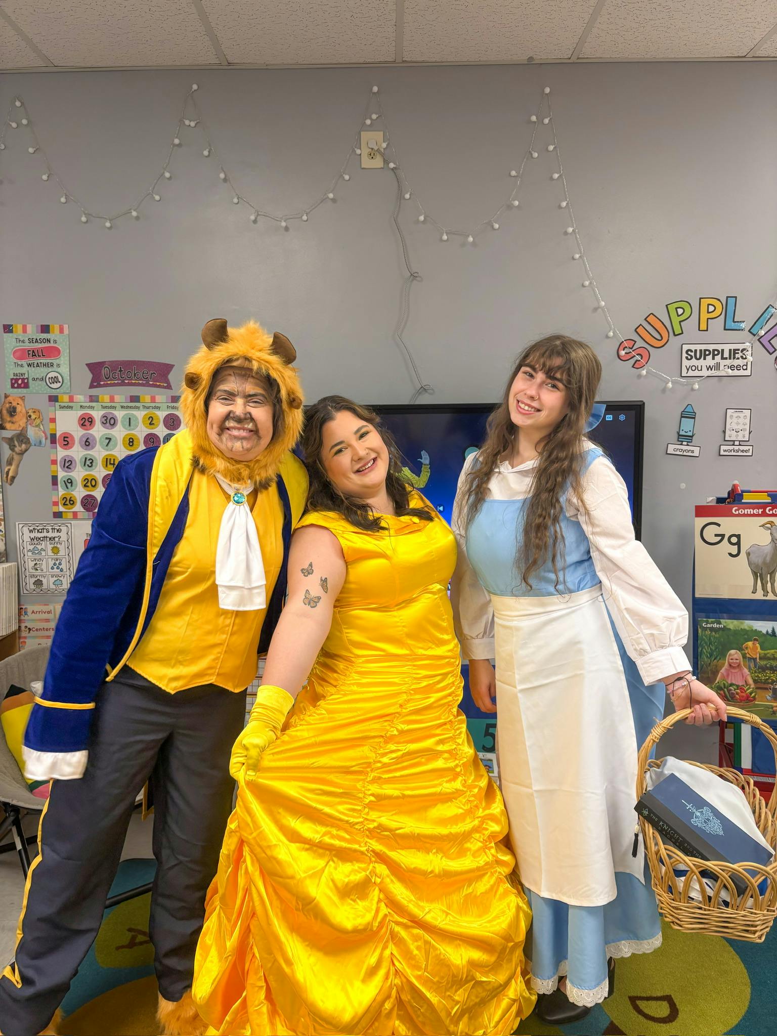 Three people in character costumes standing in a classroom