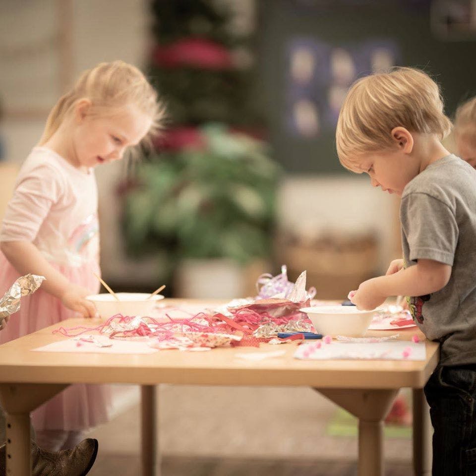 Two children standing at a table doing an art activity