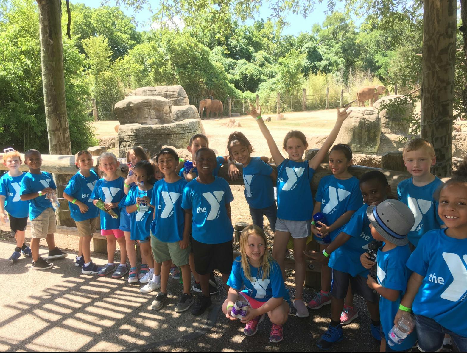 Group of children and teens in blue shirts posing outdoors