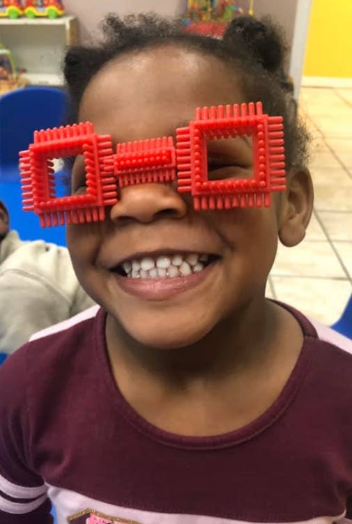 Child wearing red toy glasses
