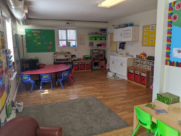 Classroom with small tables and chairs, storage units, and wall decorations