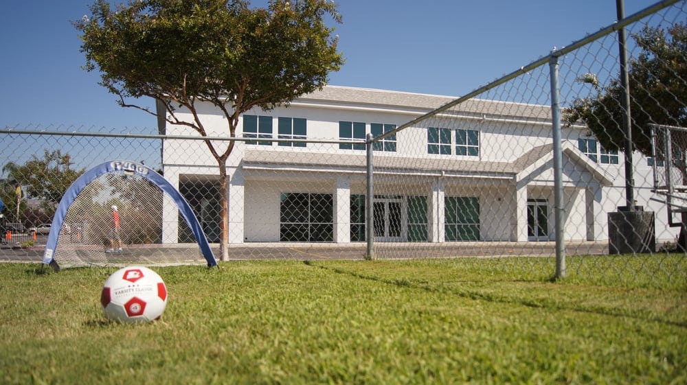 Soccer ball and small goal on grass in front of a building