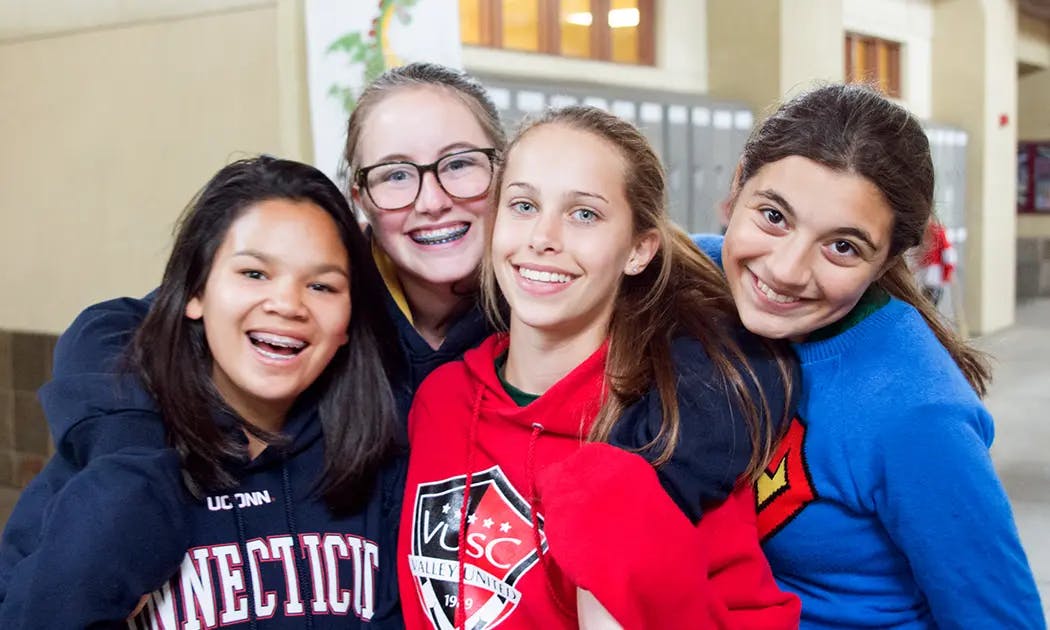 Four smiling teens posing for a photo