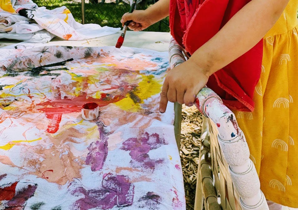 Child painting on a large canvas with various colors