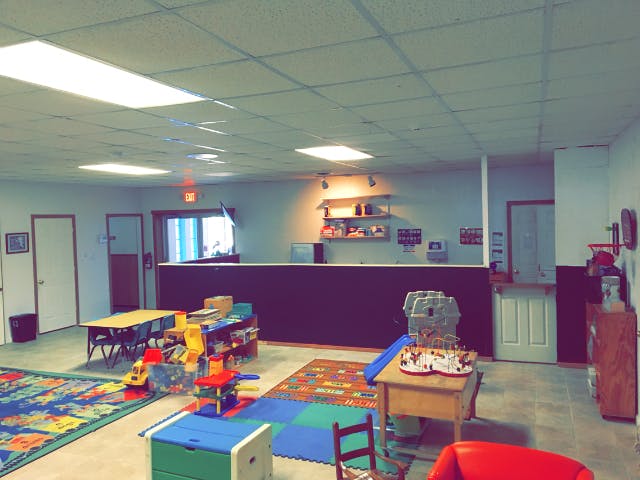 Playroom with tables, chairs, and toys on colorful rugs