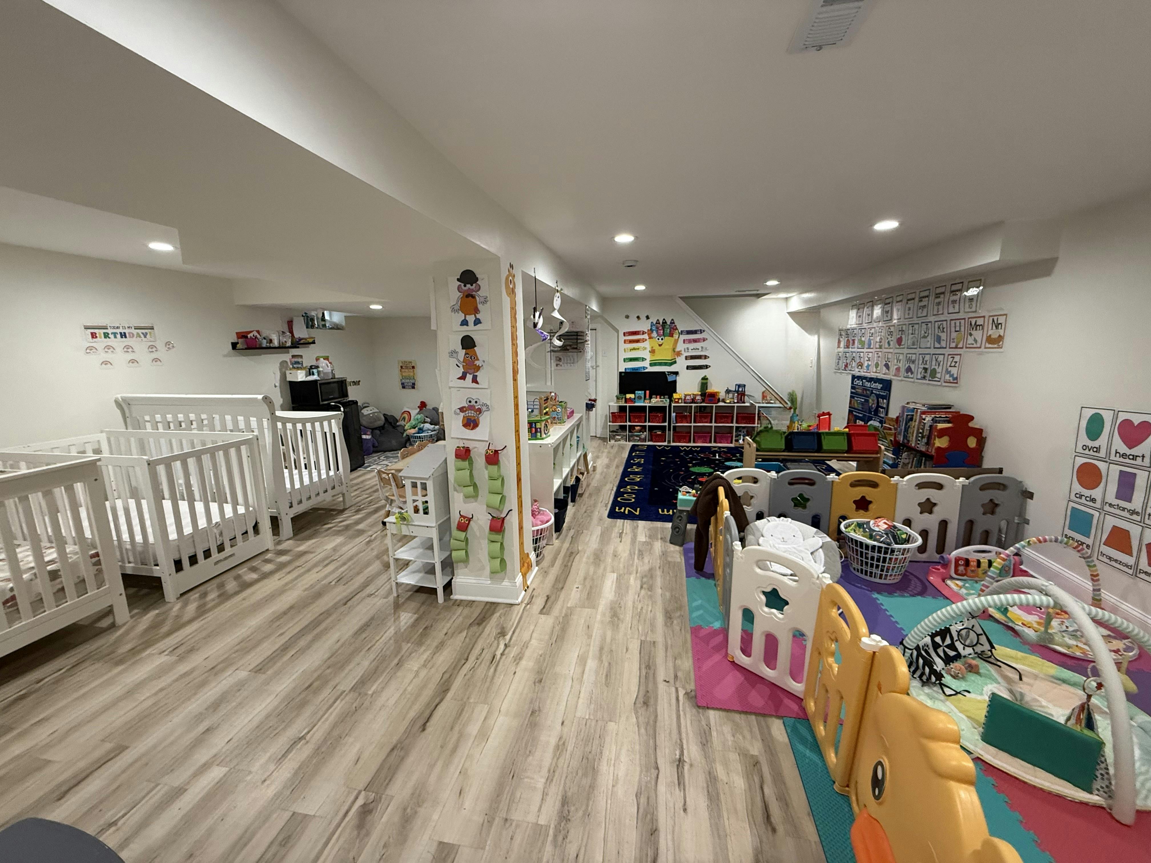 Childcare room with baby cribs and an enclosed play area with activity mats