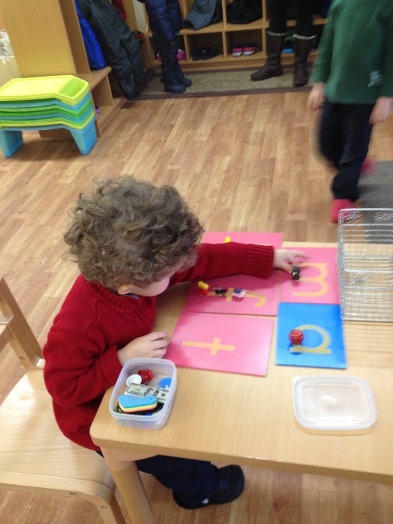 Child with curly hair playing with learning materials at a table