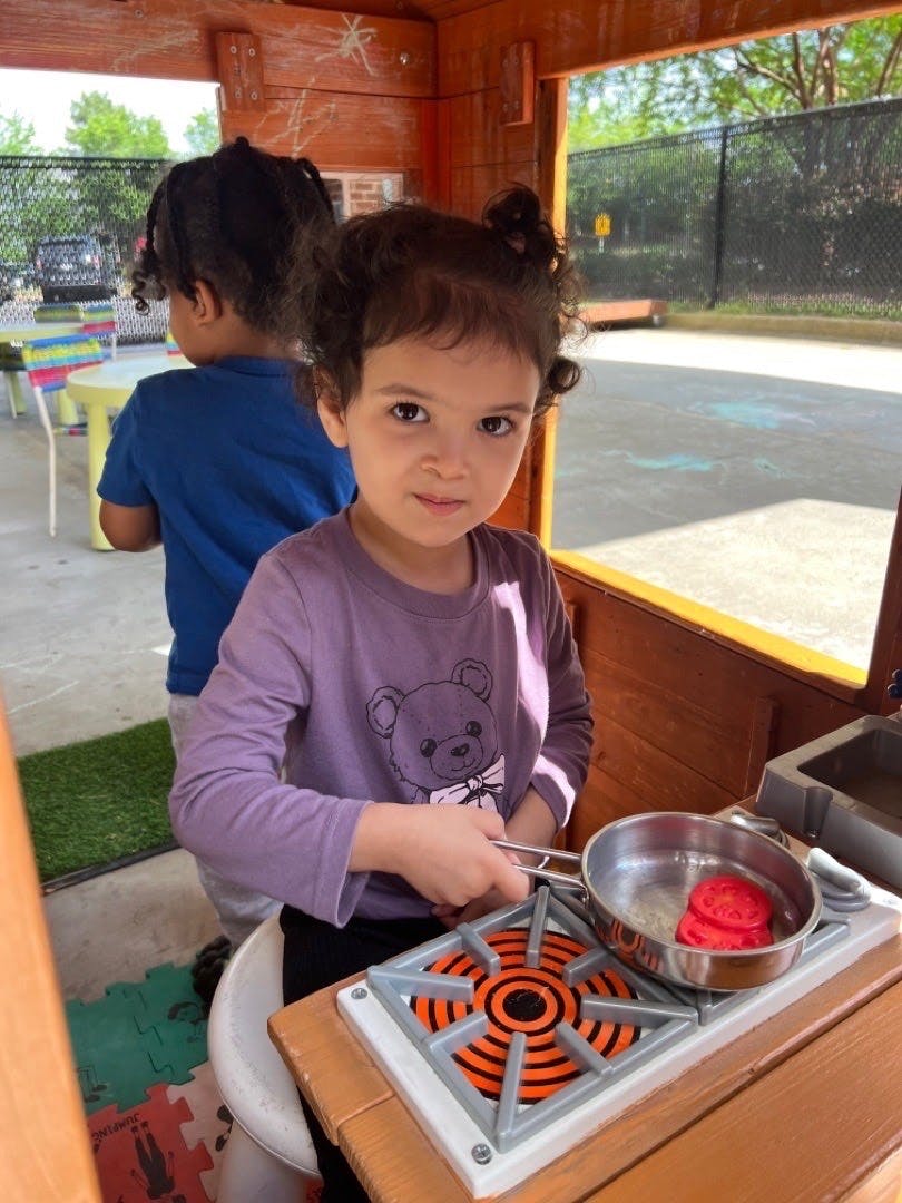 Child playing with a toy stove and pan