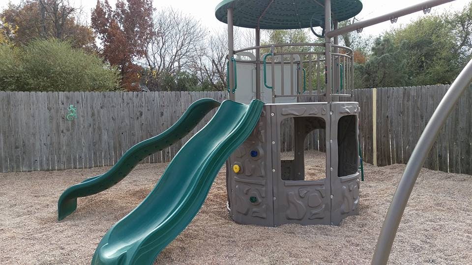 Playground with two green slides and a climbing structure