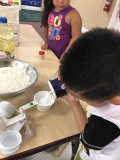 Child pouring from a container into a measuring cup