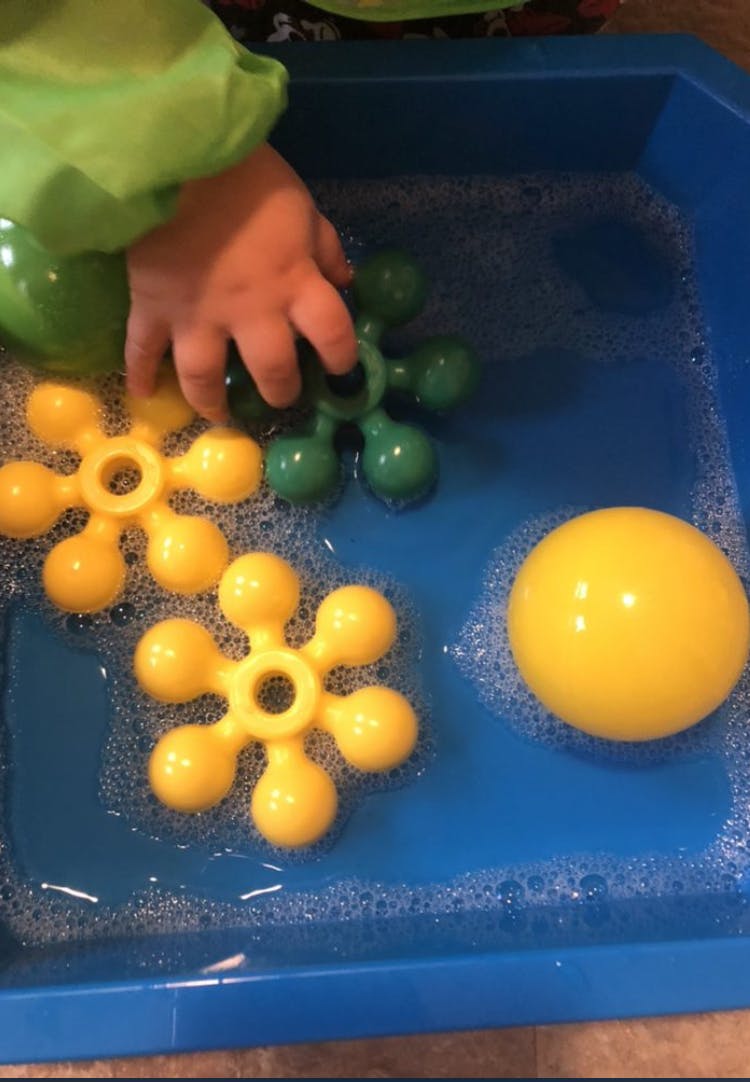 Child's hand playing with toys in a tub of water