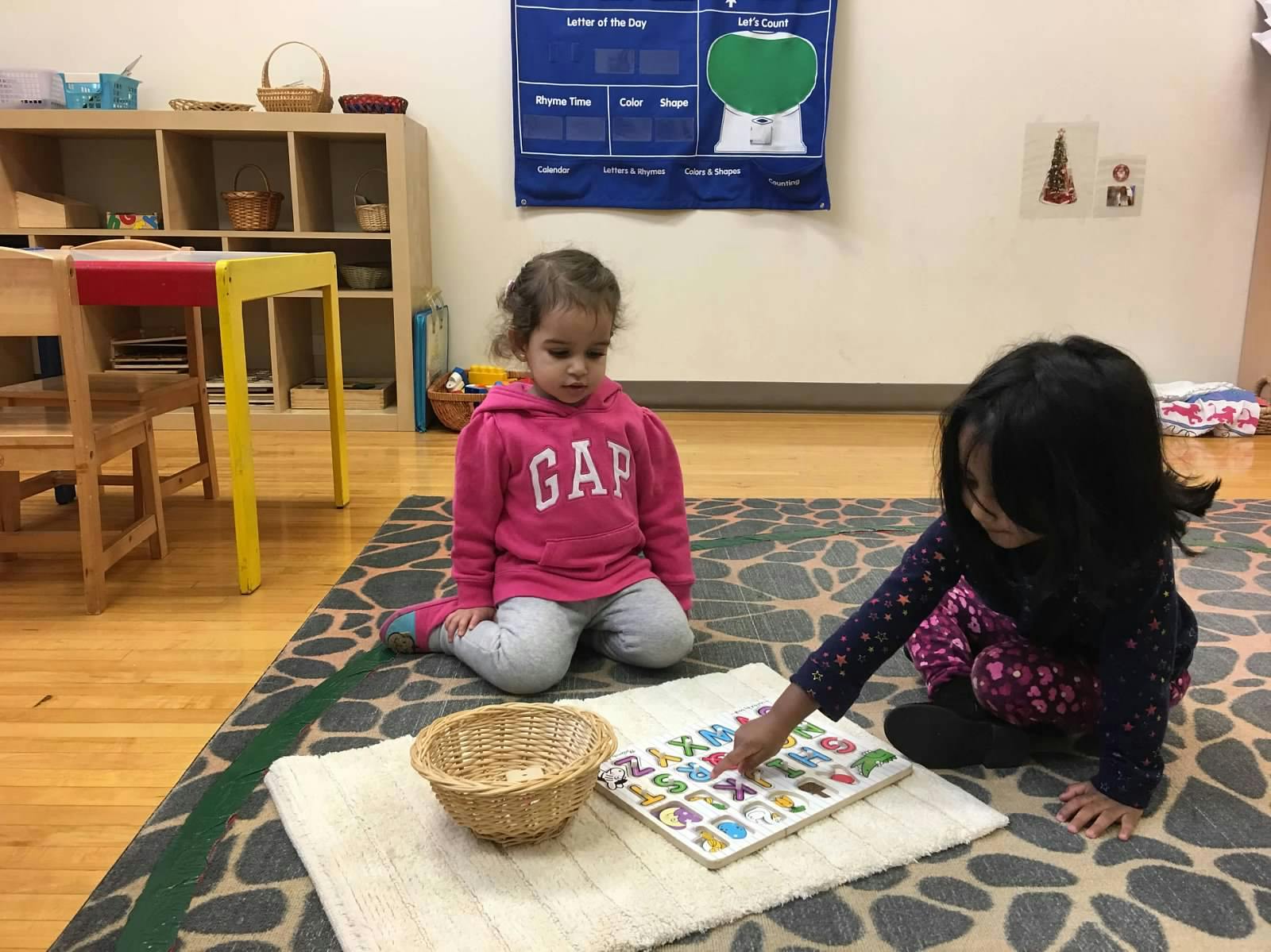 Two children playing with a letter puzzle on a rug
