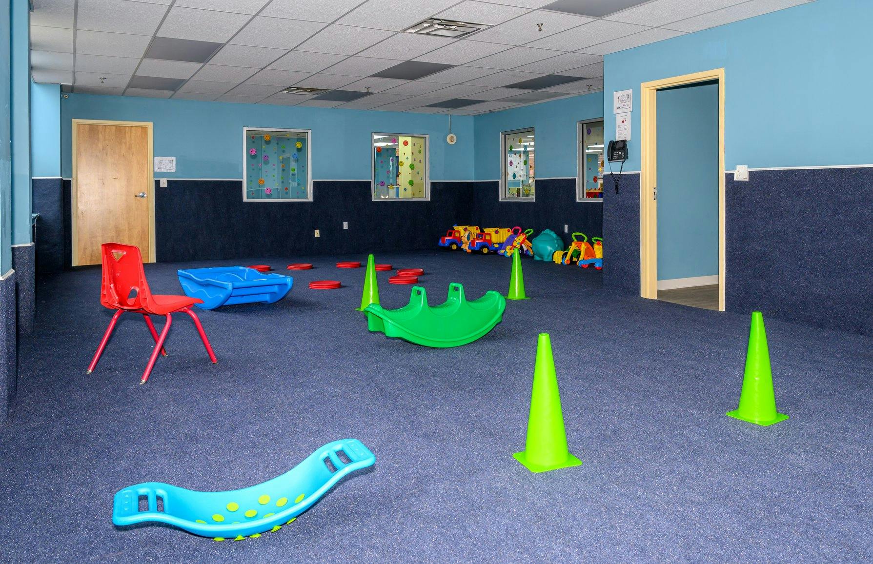 Playroom with plastic toys, rockers, and cones on carpet