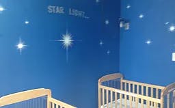 Blue wall with star decals and two cribs
